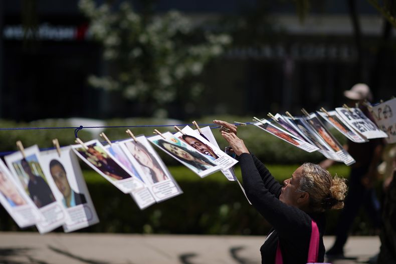 Una persona cuelga una fotografía de una persona desaparecida en una fila a lo largo de Paseo de la Reforma durante una manifestación para exigir al gobierno que haga más para localizar a sus seres queridos, durante el Día Internacional de las Víctimas de Desapariciones Forzadas, el miércoles 30 de agosto de 2023, en Ciudad de México. (AP Foto/Eduardo Verdugo, Archivo)