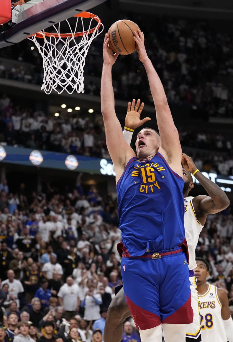 El serbio Nikola Jokic, de los Nuggets de Denver, realiza una clavada frente a LeBron James, de los Lakers de Los Ángeles, el sábado 20 de abril de 2024 (AP Foto/Jack Dempsey)