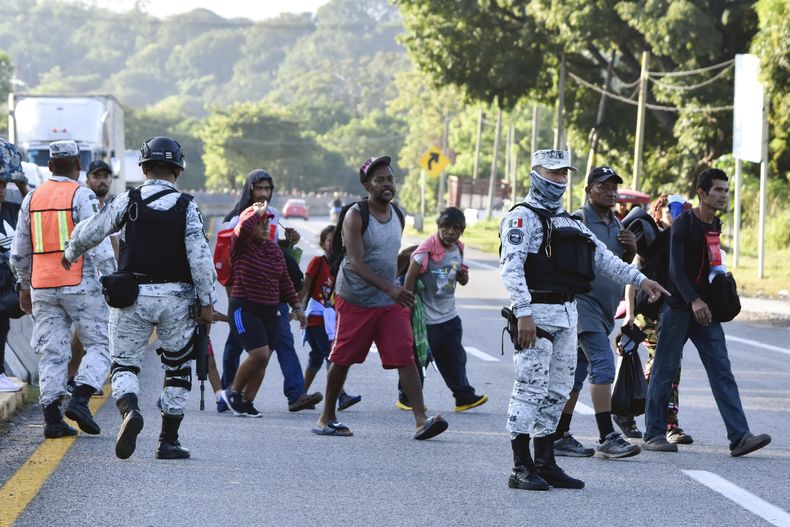 Agentes de la Guardia Nacional mexicana para el tráfico para que migrantes crucen a su llegada a pie a Huehuetán, México, el martes 31 de octubre de 2023, en su camino hacia Estados Unidos. Los migrantes dicen que han solicitado permisos temporales de tránsito en Tapachula pero no los consiguieron, algunos después de esperar hasta dos meses, y continuaron su camino sin documentación porque no podían seguir pagando ni la comida ni el alojamiento. (AP Foto/Édgar Clemente)