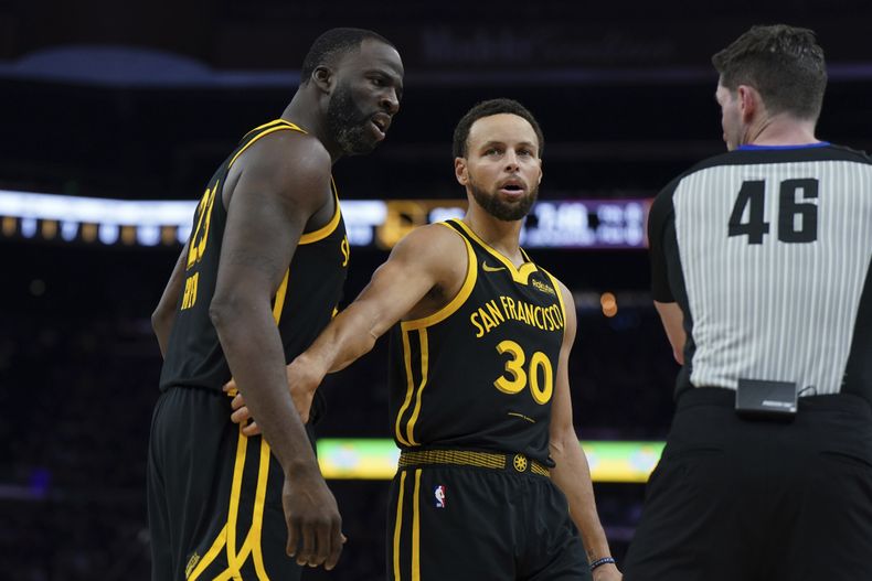 Stephen Curry, de los Warriors de Golden State, trata de controlar a su compañero Draymond Green, en el encuentro del sábado 11 de noviembre de 2023, ante los Cavaliers de Cleveland (AP Foto/Loren Elliott)