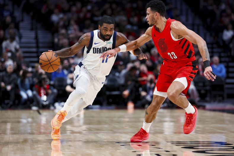 Kyrie Irving, de los Mavericks de Dallas, conduce la pelota frente a su rival de los Trail Blazers de Portland Toumani Camara durante la primera mitad del juego de la NBA que enfrentó a ambos equipos, el 8 de diciembre de 2023, en Portland, Oregon. (AP Foto/Howard Lao)