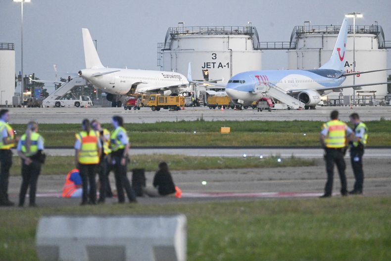 Agentes de policía, en la pista del aeropuerto de Stutgart mientras activistas climáticos realizaron protestas en varios aeropuertos de Alemania, el 15 de agosto de 2024, obligando a la suspensión temporal de varios vuelos. (Marius Bulling/dpa vía AP)