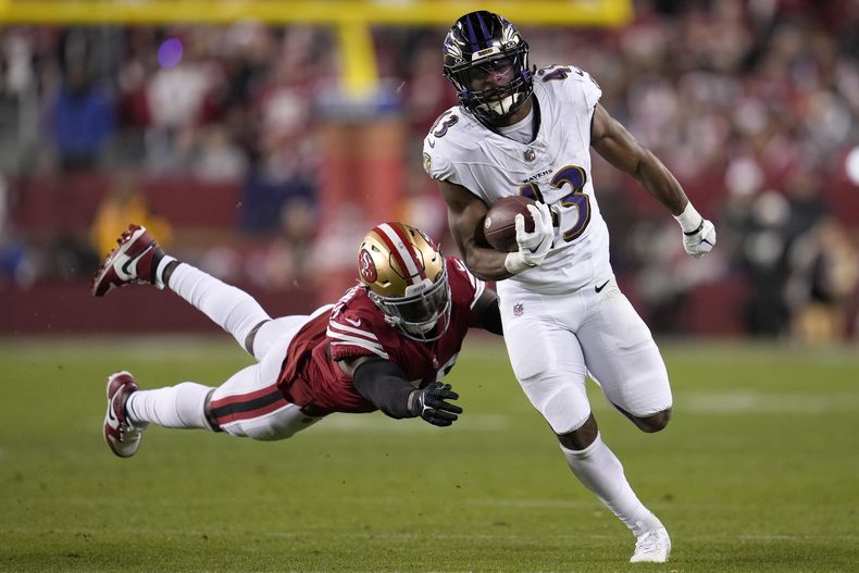 El corredor de los Ravens de Baltimore Justice Hill corre con el balón frente al linebacker de los 49ers de San Francisco Demetrius Flannigan-Fowles en el encuentro del lunes 25 de diciembre del 2023. (AP Foto/Godofredo A. Vásquez)