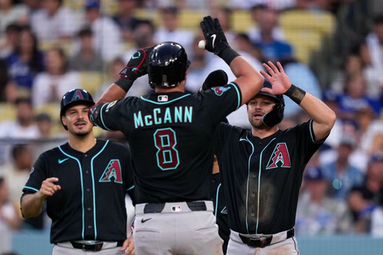 James McCann, centro, de los Diamondbacks de Arizona, es felicitado por Nolan Arenado, izquierda, y Tim Tawa después de batear un cuadrangular de tres carreras durante la sexta entrada del juego de béisbol de Grandes Ligas contra los Dodgers de Los Ángeles, el sábado 11 de julio de 2026, en Los Ángeles. (AP Foto/Mark J. Terrill)