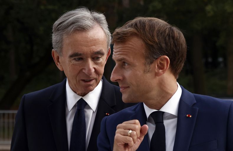 ARCHIVO - El director ejecutivo del conglomerado de lujo LVMH, Bernard Arnault, izquierda, y el presidente francés, Emmanuel Macron, llegan a la Fundación Louis Vuitton para visitar la exposición La colección Morozov, iconos del arte moderno en París, el martes 21 de septiembre de 2021. Un importante papel de patrocinio destinado para pulir la imagen de los Juegos Olímpicos de Verano de París 2024 y de la capital francesa, es un nuevo capítulo en la especialidad de LVMH de vender exclusividad a gran escala bajo su presidente y director ejecutivo, Arnault. (Yoan Valat/Pool Photo via AP, archivo)