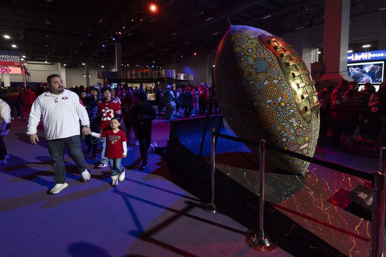 Aficionados caminan junto a una escultura de un balón de fútbol americano decorado en el NFL Experience en Las Vegas antes del Super Bowl 58 en Las Vegas el sábado 10 de febrero del 2024. (AP Foto/Gregory Bull)