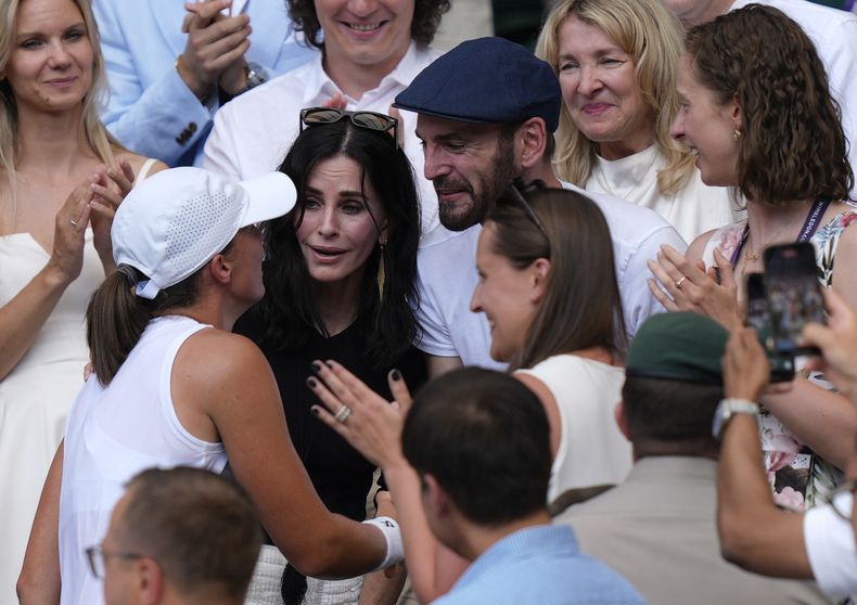 Courteney Cox, al centro, y Johnny McDaid celebran con la polaca Iga Swiatek mientras saluda a sus entrenadores, amigos y familiares después de vencer a Amanda Anisimova de EE. UU. para ganar la final individual femenina en el Campeonato de Tenis de Wimbledon en Londres, el sábado 12 de julio de 2025. (Andrew Matthews, PA vía AP)