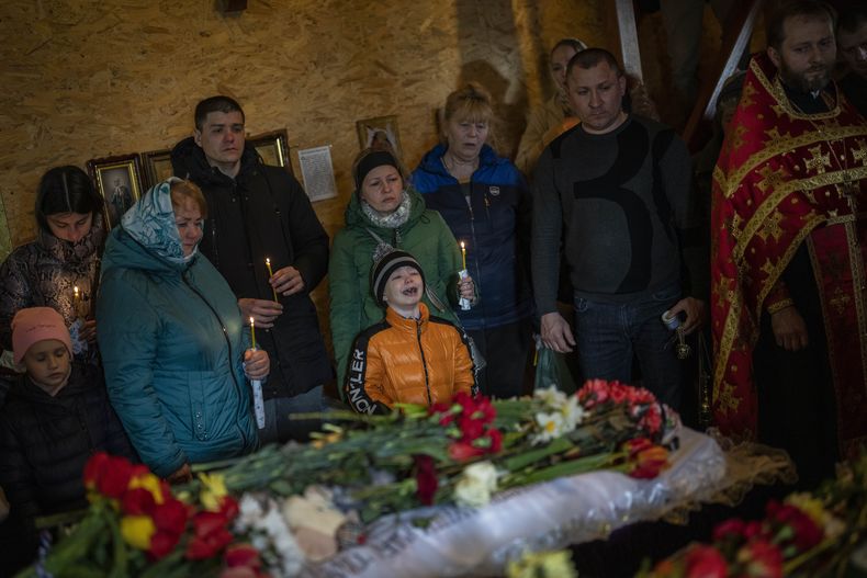 Mykhayl Shulha, centro, llora junto al ataúd de su hermana Sofia Shulha durante un funeral en Uman, Ucrania, el domingo 30 de abril de 2023. (AP Foto/Bernat Armangue)