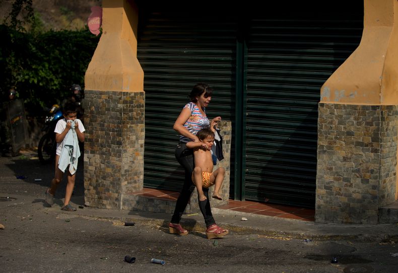 Una mujer busca refugiarse con su hijo del gas lacrim&oacute;geno que lanzaron soldados contra manifestantes durante una protesta antigubernamental en Caracas, Venezuela, el s&aacute;bado 26 de abril de 2014. Las autoridades anunciaron la captura de un in