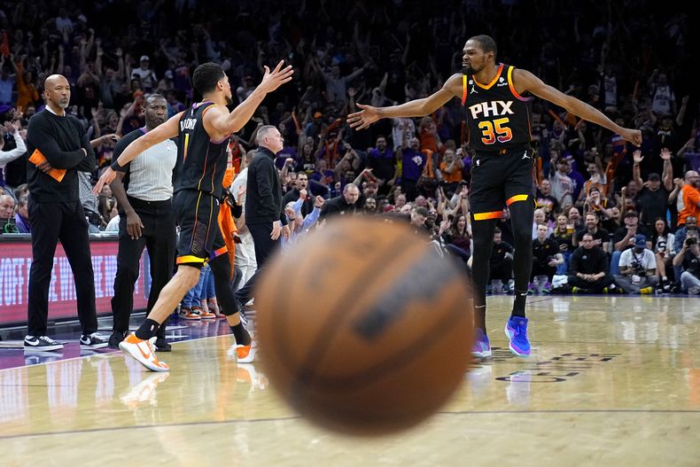 Devin Booker (izquierda) festeja un enceste con su compañero de los Suns de Phoenix, Kevin Durant, en el tercer partido de las semifinales de la Conferencia Oeste frente a los Nuggets de Denver, el viernes 5 de mayo de 2023 (AP Foto/Matt York)