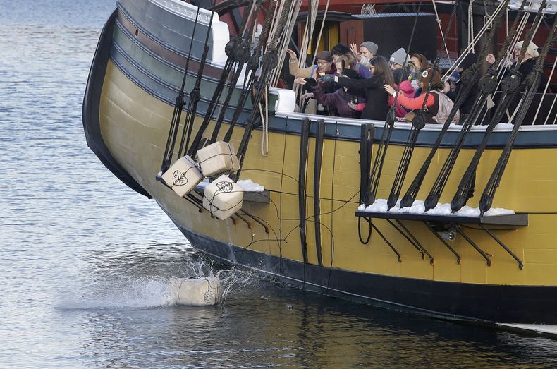ARCHIVO-En esta foto del lunes 11 de diciembre de 2017, visitantes del Museo del Motín del Té de Boston lanzan réplicas de históricos contenedores de té desde una réplica del buque Beaver, en Boston. (AP Foto/Steven Senne, Archivo)
