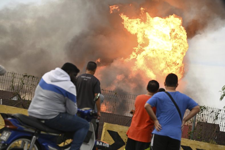 Vecinos miran un incendio en Putra Heights, en el centro de Selangor, Malasia, el martes 1 de abril de 2025. (AP Foto/Amir Afiq)