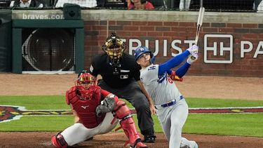 El infielder de los Dodgers de Los Ángeles, Enrique Hernández, completa su swing tras conectar un cuadrangular de dos carreras mientras el receptor de los Bravos de Atlanta, Drake Baldwin (30), y el ampáyer James Hoye observan durante la cuarta entrada del tercer juego de la serie divisional de la Liga Nacional de béisbol, el martes 6 de octubre de 2026, en Atlanta. (Foto AP/Mike Stewart)