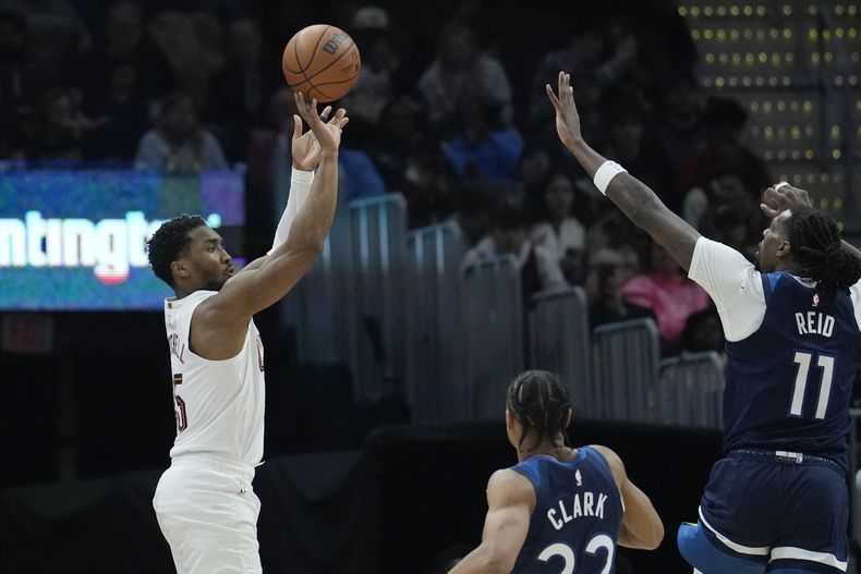 El base de los Cavaliers de Cleveland Donovan Mitchell lanza el balón sobre el base de los Timberwolves de Minnesota Jaylen Clark y Naz Reid en el encuentro del lunes 10 de febrero del 2025. (AP Foto/Sue Ogrocki)