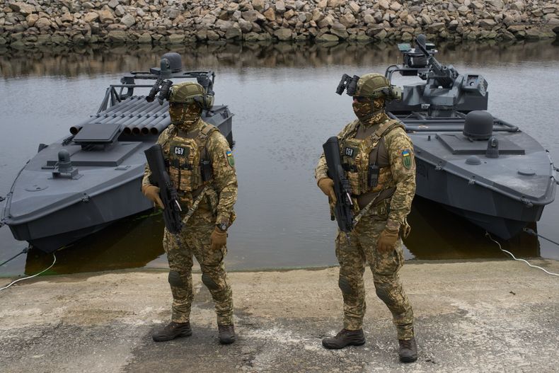 Miembros del Servicio de Seguridad de Ucrania se ven de pie junto a drones acuáticos Sea Baby, durante una demostración en un lugar no revelado en Ucrania, el viernes 17 de octubre de 2025. (AP Foto/Efrem Lukatsky)