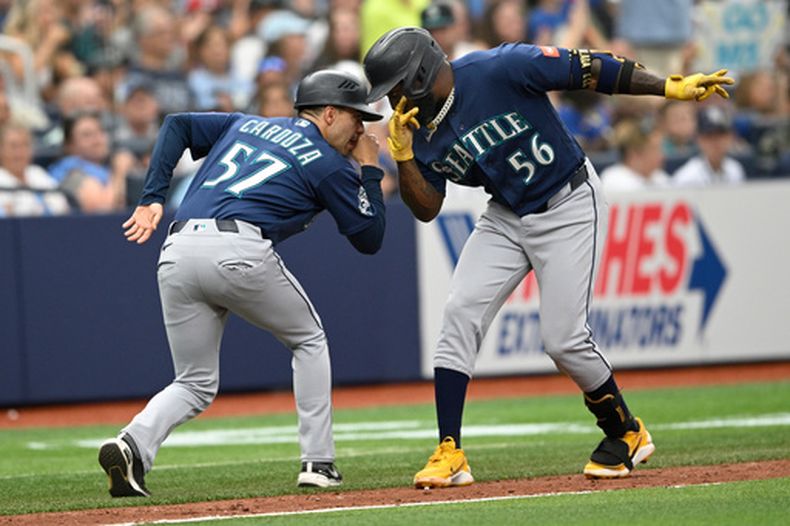 Randy Arozarena de los Marineros de Seattle celebra con el coach de tercera base Carlos Cardozo al correr las bases tras su jonrón de tres carreras en la cuarta ante los Rays de Tampa Bay el domingo 12 de julio del 2026. (AP Foto/Phelan M. Ebenhack)