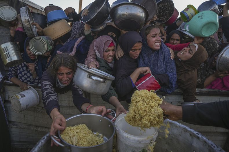 Niñas palestinas luchan por recibir alimentos donados en un centro de distribución en Jan Yunis, en la Franja de Gaza, el viernes 6 de diciembre de 2024. (Foto AP /Abdel Kareem Hana)