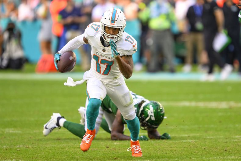 ARCHIVO - Jaylen Waddle (17), wide receiver de los Dolphins de Miami, corre con el balón dejando atrás al linebacker Quincy Williams (56), de los Jets de Nueva York, durante un partido de la NFL, el domingo 17 de diciembre de 2023, en Miami Gardens, Florida. Waddle pactó una extensión de contrato de tres años y 84,75 millones de dólares con los Dolphins, dijo a The Associated Press una persona con conocimiento del acuerdo. (AP Foto/Doug Murray, Archivo)