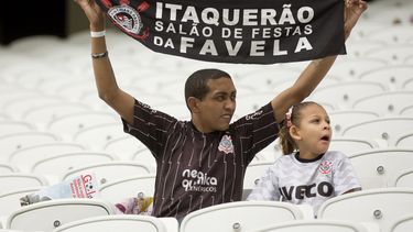 americateve | Un obrero muestra una pancarta con el mensaje "Itaquerao, el vest&iacute;bulo de la favela", mientras mira un partido de pr&aacute;ctica en la construcci&oacute;n del estadio de Sao Paulo para la Copa del Mundo el jueves, 1 de mayo de 2014, en S
