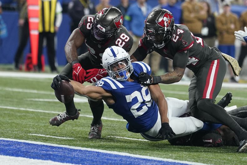 El runningback de los Colts de Indianápolis Jonathan Taylor (28) se estira para un touchdowns mientras el safety de los Buccaneers de Tampa Bay Christian Izien (29) y el cornerback Carlton Davis III (24) tratan de impedirlo durante la 2da mitad del juego de NFL, el domingo 26 de noviembre de 2023, en Indianápolis. (AP Foto/Michael Conroy)