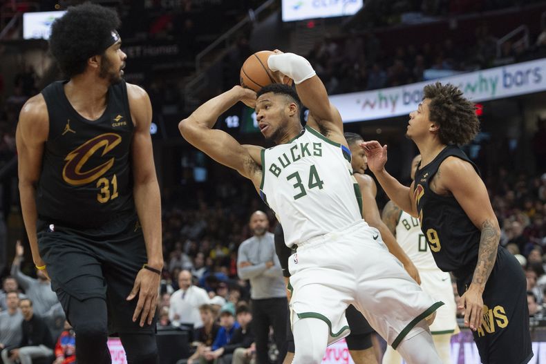 Giannis Antetokounmpo, de los Bucks de Milwaukee, busca enviar un pase entre Jarrett Allen (31) y Craig Porter, de los Cavaliers de Cleveland, en el encuentro del viernes 29 de diciembre de 2023 (AP Foto/Phil Long)