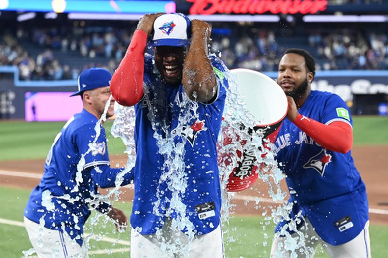 El jardinero de los Azulejos de Toronto Jesús Sánchez es bañado con Gatorade por sus compañeros Myles Straw y Vladimir Guerrero tras vencer a los Guardianes de Cleveland el domingo 26 de abril del 2026. (Jon Blacker/The Canadian Press via AP)