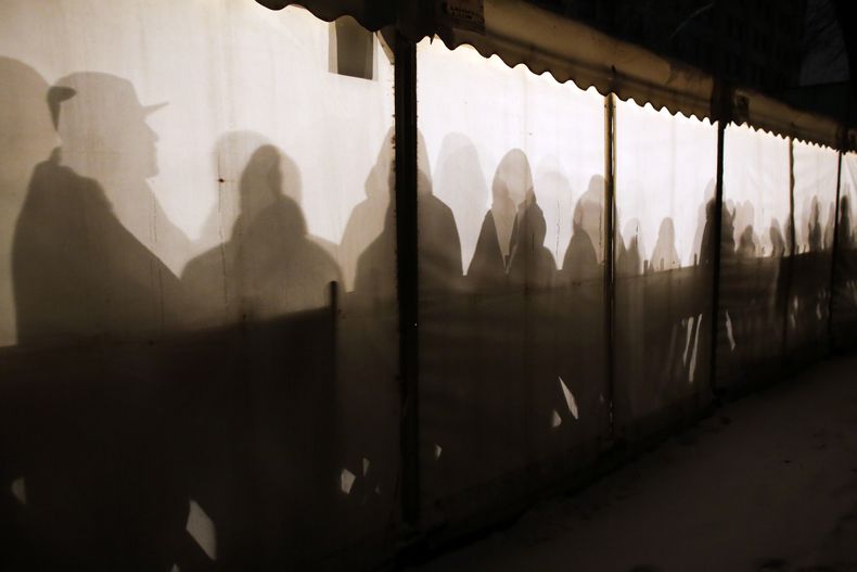 En esta imagen del miércoles 6 de enero de 2016 se pueden ver las siluetas de migrantes mientras se calientan dentro de una carpa en lo que esperan a recibir una cita en el centro de registro para refugiados y solicitantes de asilo, en Berlín. (AP Foto/Markus Schreiber, Archivo)