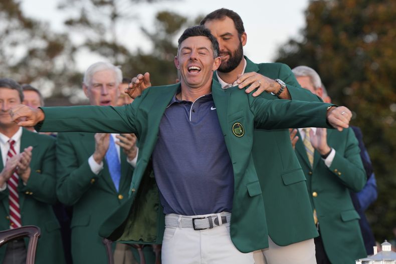Scottie Scheffler le pone el saco verde de campeón del Masters al norirlandés Rory McIlroy tras ganar el torneo en Augusta el domingo 13 de abril del 2025. (AP Foto/David J. Phillip)