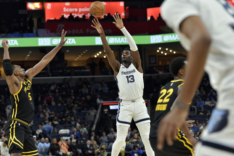 Jaren Jackson Jr. (13), de los Grizzlies de Memphis, dispara ante el intento desesperado de defensa de Kevon Looney (5), de los Warriors de Golden State, en la segunda mitad del juego de baloncesto de la NBA, el lunes 15 de enero de 2024, en Memphis, Tennessee. (AP Foto/Brandon Dill)