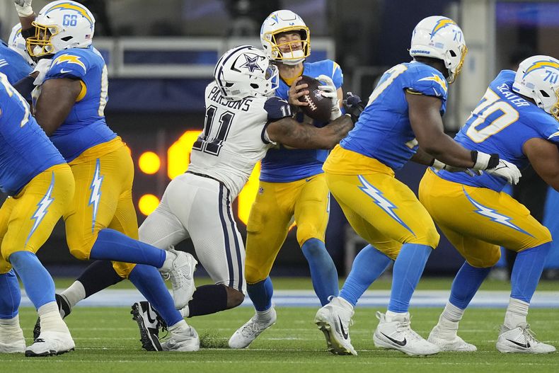 El linebacker Micah Parsons (11), de los Cowboys de Dallas, captura al quarterback de los Chargers de Los Ángeles, Justin Herbert, centro, durante la segunda mitad del juego de la NFL, el lunes 16 de octubre de 2023, en Inglewood, California. (AP Foto/Mark J. Terrill)