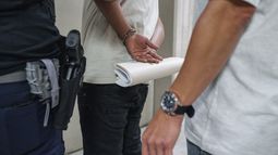 Un hombre sostiene sus documentos migratorios mientras se encuentra esposado después de ser detenido por agentes del Servicio de Inmigración y Control de Aduanas fuera de un tribunal de inmigración, el 17 de junio de 2025, en Nueva York. (AP Foto/Olga Fedorova, Archivo)