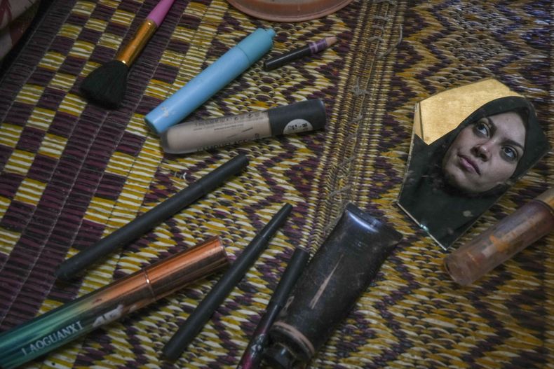 Alaa Hamami mira a un trozo de espejo roto mientras posa para un retrato junto a sus deteriorados cosméticos, en su carpa de un campamento para palestinos desplazados en Deir al-Balah, Franja de Gaza, el 18 de diciembre de 2024. (AP Foto/Abdel Kareem Hana)