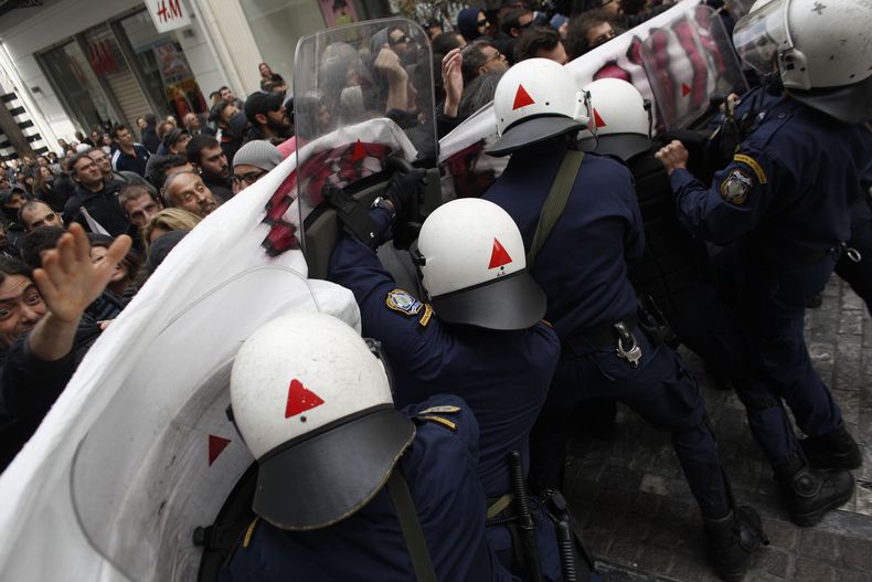 Polic&iacute;as antimotines tratan de dispersar a manifestantes durante una protesta contra la apertura de tiendas en domingo y la extensi&oacute;n de horas laborales, el domingo 13 de abril de 2014, en Atenas. (Foto AP/Kostas Tsironis)