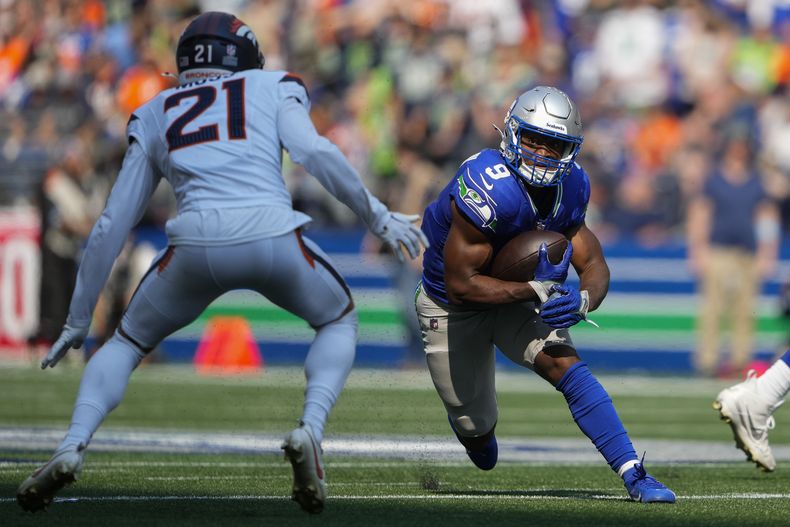 Kenneth Walker III (9), running back de los Seahawks de Seattle, corre con el balón mientras el cornerback Riley Moss (21), de los Broncos de Denver, intenta detenerlo durante la segunda mitad del juego de la NFL el domingo 8 de septiembre de 2024, en Seattle. (AP Foto/Lindsey Wasson)