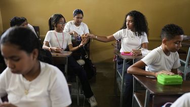 Una estudiante comparte su desayuno con una compañera en una escuela de Coro, Venezuela, el miércoles 25 de junio de 2025. (AP Foto/Ariana Cubillos)