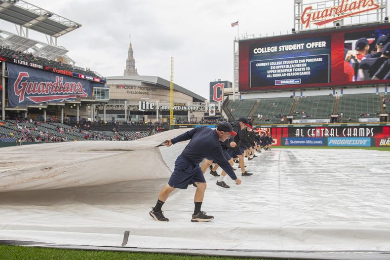El equipo de mantenimiento de terreno de los Guardianes de Cleveland remueven la lona del cuadro interior antes del juego entre los Guardianes y los Astros de Houston, en Cleveland, el domingo 29 de septiembre de 2024. (AP Foto/Phil Long)