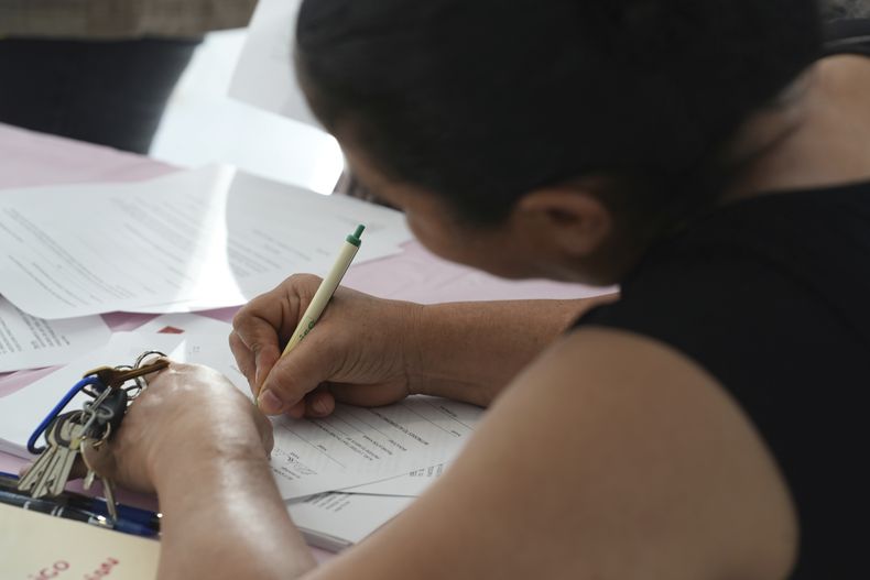 Una madre joven firma un documento que da a Nora Sandigo la custodia legal de sus hijos menores de edad en caso de que sea detenida o deportada por las autoridades de inmigración de Estados Unidos, el domingo 19 de enero de 2025, en Miami. (AP Foto/Marta Lavandier,file)
