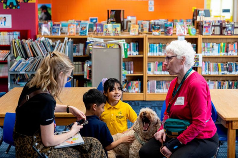 Yesli, en el centro a la derecha, acaricia a Sage, una perra de terapia, en la escuela elemental Valley View el 29 de abril de 2026, en Columbia Heights, Minnesotta. (Ellen Schmidt/MinnPost via AP)
