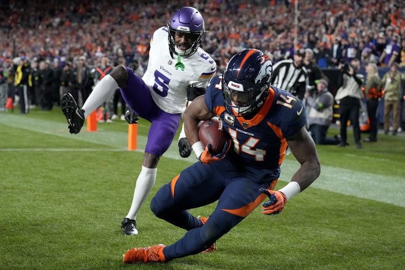 Courtland Sutton (14), wide receiver de los Broncos de Denver, consigue una anotación superando en el brinco a Mekhi Blackmon (5), cornerback de los Vikings de Minnesota, durante la segunda mitad del juego de la NFL el domingo 19 de noviembre de 2023, en Denver. (AP Foto/David Zalubowski)