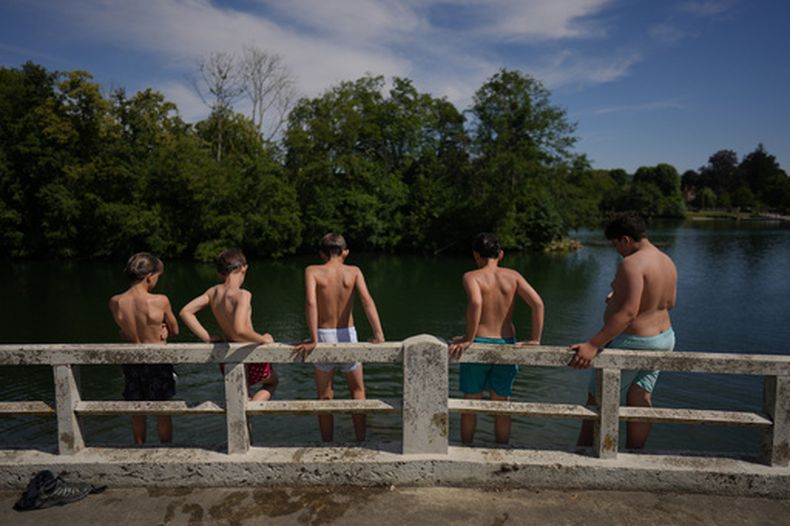 Varios niños se preparan para saltar al río Sena en Samois-sur-Seine, al sur de París, el viernes 19 de junio de 2026. (AP Foto/Thibault Camus)