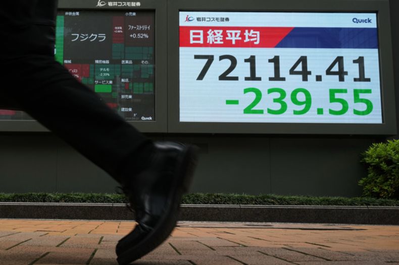 Un hombre pasa junto a una pantalla que muestra el índice Nikkei 225 de Japón en una correduría de valores de Tokio, el martes 23 de junio de 2026. (AP Foto/Hiro Komae)