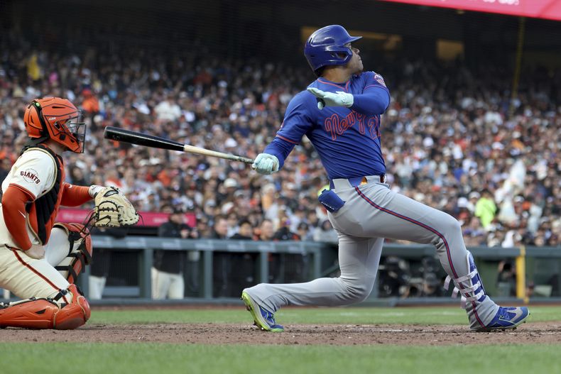 Juan Soto, derecha, de los Mets de Nueva York, batea un jonrón frente al receptor de los Gigantes de San Francisco, Patrick Bailey, izquierda, durante la séptima entrada del juego de béisbol de Grandes Ligas, el domingo 27 de julio de 2025, en San Francisco. (AP Foto/Jed Jacobsohn)