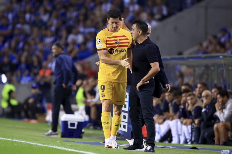 El delantero del Barcelona Robert Lewandowski camina frente al técnico Xavi Hernández tras ser sustituido durante el partido contra el FC Porto en un partido de la Liga de Campeones, el miércoles 4 de octubre de 2023, en Oporto. (AP Foto/Luis Vieira)