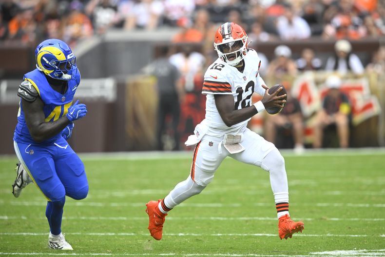 Shedeur Sanders (12), quarterback de los Browns de Cleveland, corre tratando de eludir al linebacker Jamil Muhammad (45), de los Rams de Los Ángeles, en la segunda mitad del partido de pretemporada de la NFL el sábado 23 de agosto de 2025, en Cleveland. (AP Foto/David Richard)