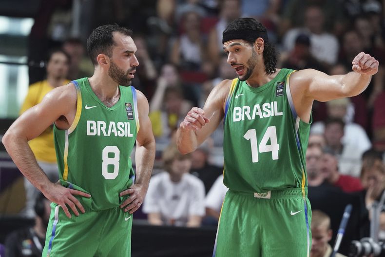 Vitor Benite (izquierda) y Leo Meindil, de Brasil conversan durante el partido clasificatorio al baloncesto de los Juegos Olímpicos entre Letonia y Brasil, en Riga, Letonia, el domingo 7 de julio de 2024. (AP Foto/Roman Koksarov)