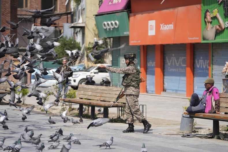 Un soldado indio alimenta palomas en un mercado, al día siguiente de que India y Pakistán acordaran un cese el fuego tras conversaciones lideradas por Estados Unidos para poner fin a la confrontación militar más grave entre los rivales con armas nucleares en décadas, en Srinagar, en la Cachemira controlada por India, el domingo 11 de mayo de 2025. (AP Foto/Mukhtar Khan)