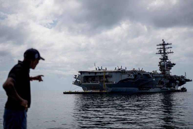 Un trabajador señala el portaaviones de la Armada estadounidense USS Nimitz atracando en el Golfo de Panamá, el lunes 30 de marzo de 2026. (Foto AP/Matias Delacroix)