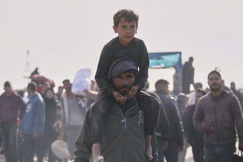 Palestinos esperan al lado de sus pertenencias en el centro de Gaza, el sábado 25 de enero de 2025, al tiempo que las fuerzas militares israelíes advierte a los palestinos no regresar al norte de Gaza. (AP Foto/Abdel Kareem Hana)