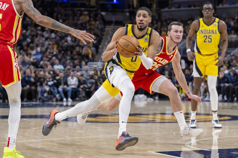 Tyrese Haliburton, base de los Pacers de Indiana, avanza hacia la cesta, frente a Garrison Matthews, de los Hawks de Atlanta, en el partido del viernes 5 de enero de 2024 (AP Foto/Doug McSchooler)