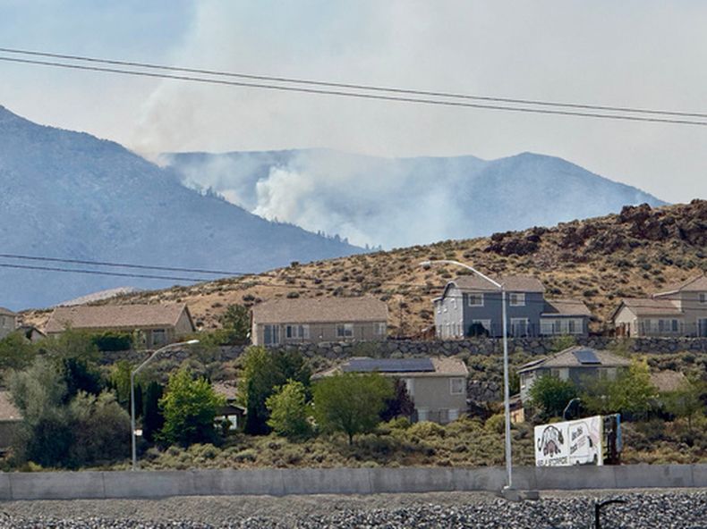 Humo se eleva a lo lejos mientras un incendio forestal arde el domingo 23 de agosto de 2026, en Reno, Nevada. (AP Foto/Haven Daley)